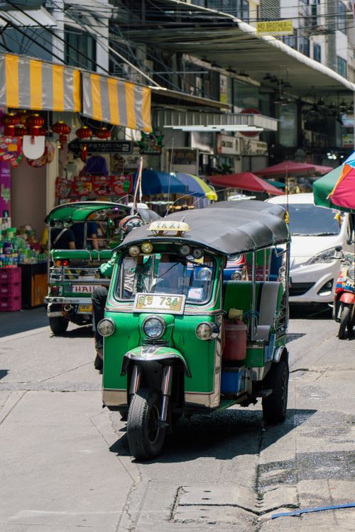 Free Tuk tuk navigating a bustling street market in Bangkok, Thailand, showcasing local culture. Stock Photo