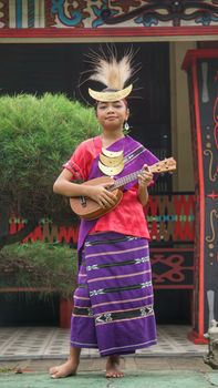 Young musician in traditional Indonesian attire playing a string instrument outdoors. - Fotografer Sidoarjo