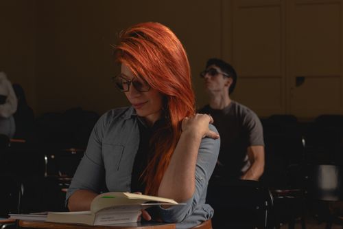 Free Young woman with red hair reading in a classroom setting, focused and thoughtful. Stock Photo