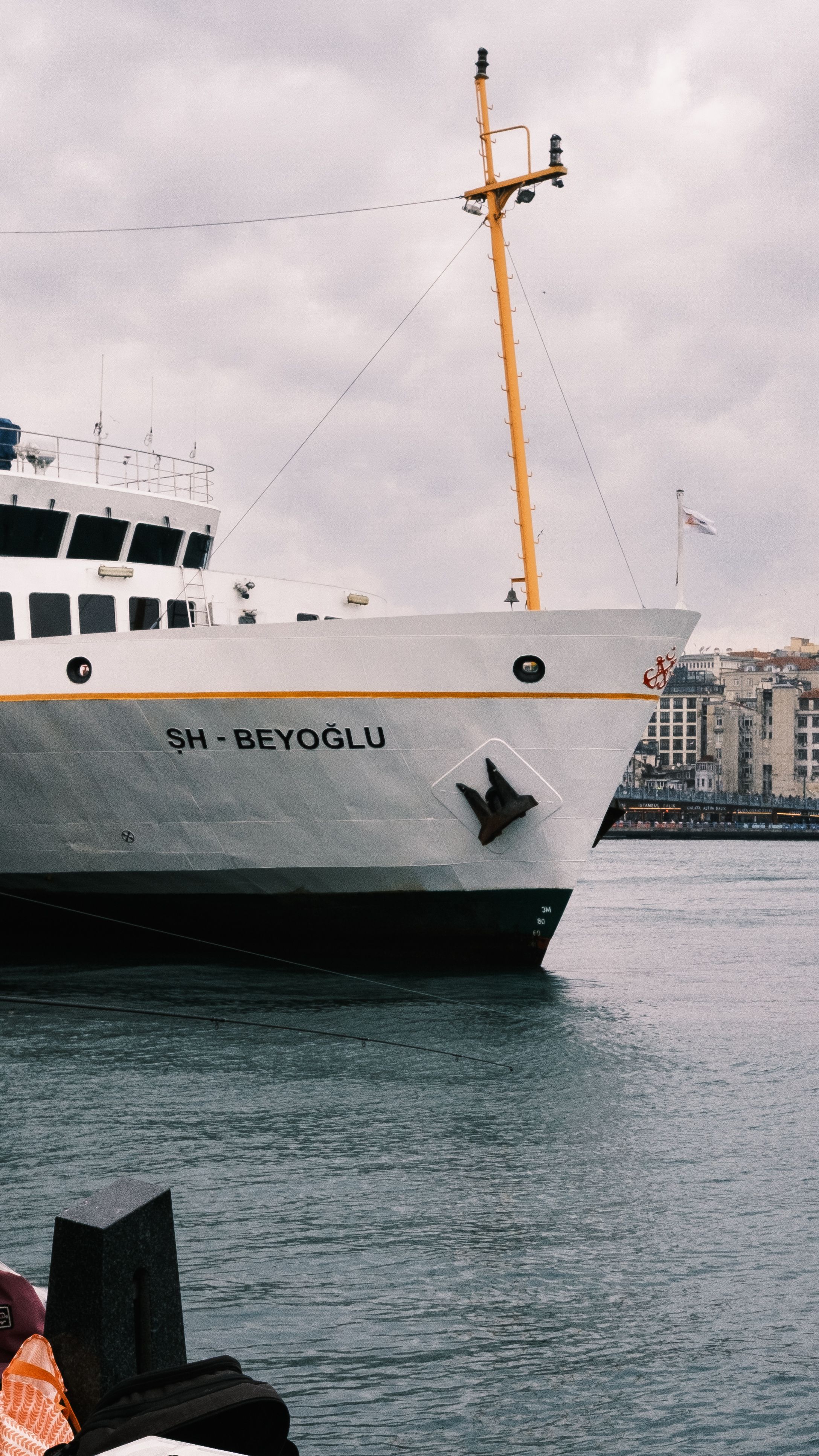 A ferry named SH - Beyoğlu docked at a harbor under cloudy skies, Istanbul.