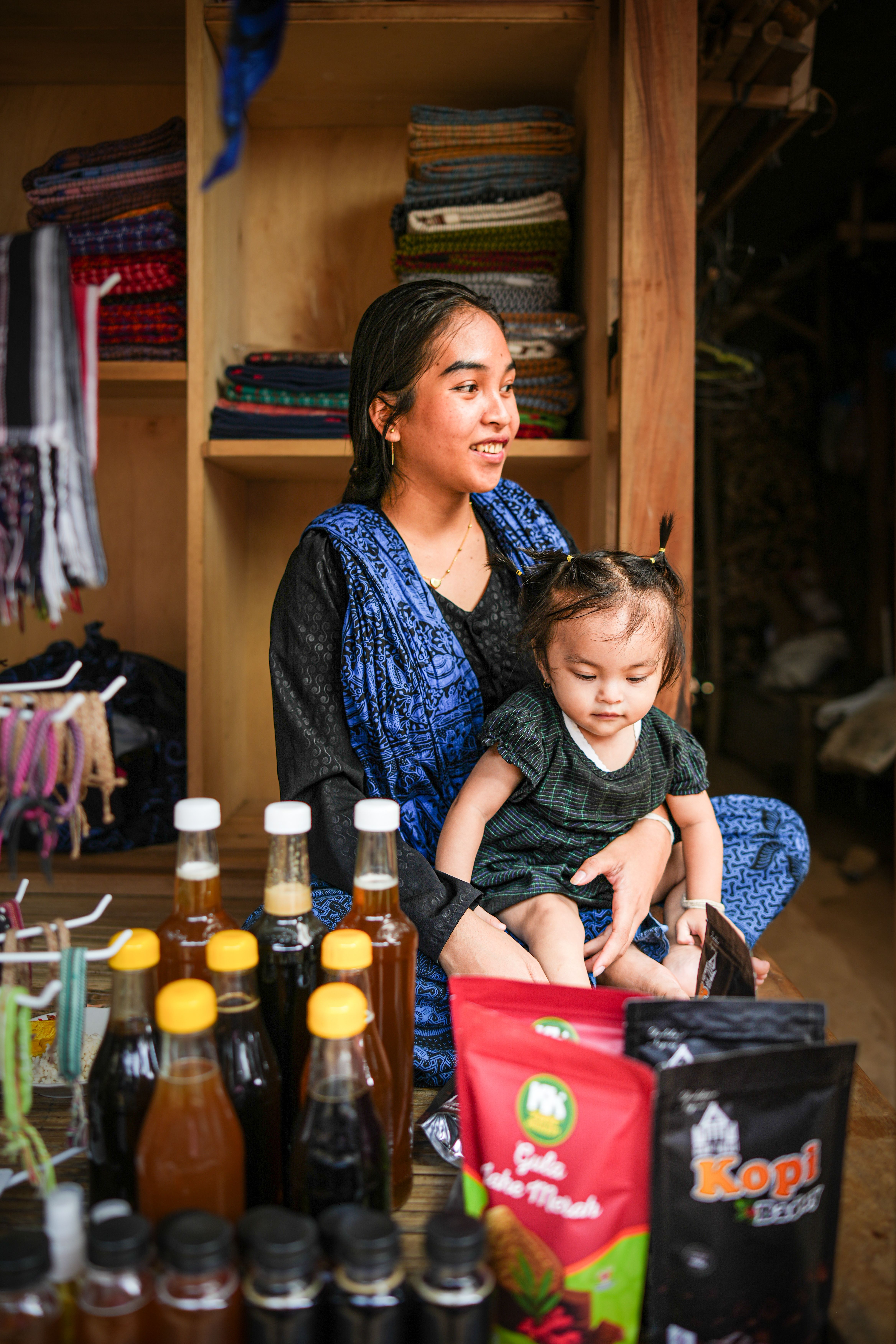 A mother and her child sitting at a local market stall in Banten, Indonesia, showcasing traditional products.
