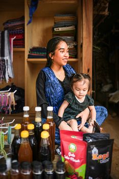 A mother and her child sitting at a local market stall in Banten, Indonesia, showcasing traditional products. - Fotografer Sidoarjo