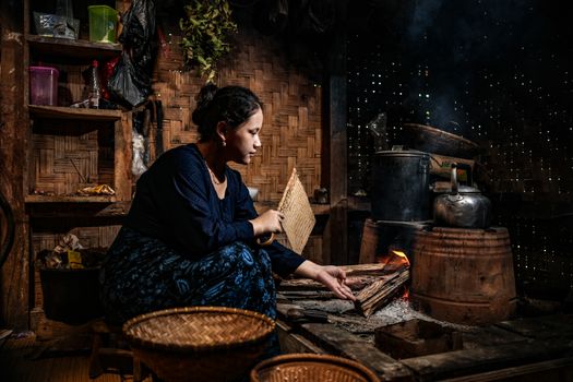 A woman tends to a wood fire in a traditional kitchen in Banten, Indonesia.