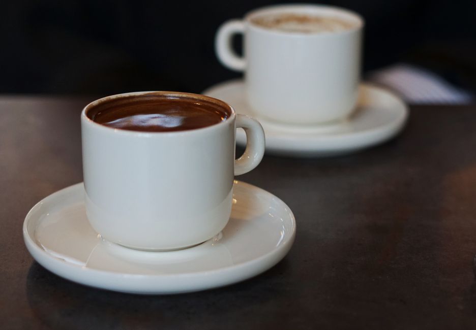 Two white cups of coffee resting on a table, creating a cozy cafe ambiance.