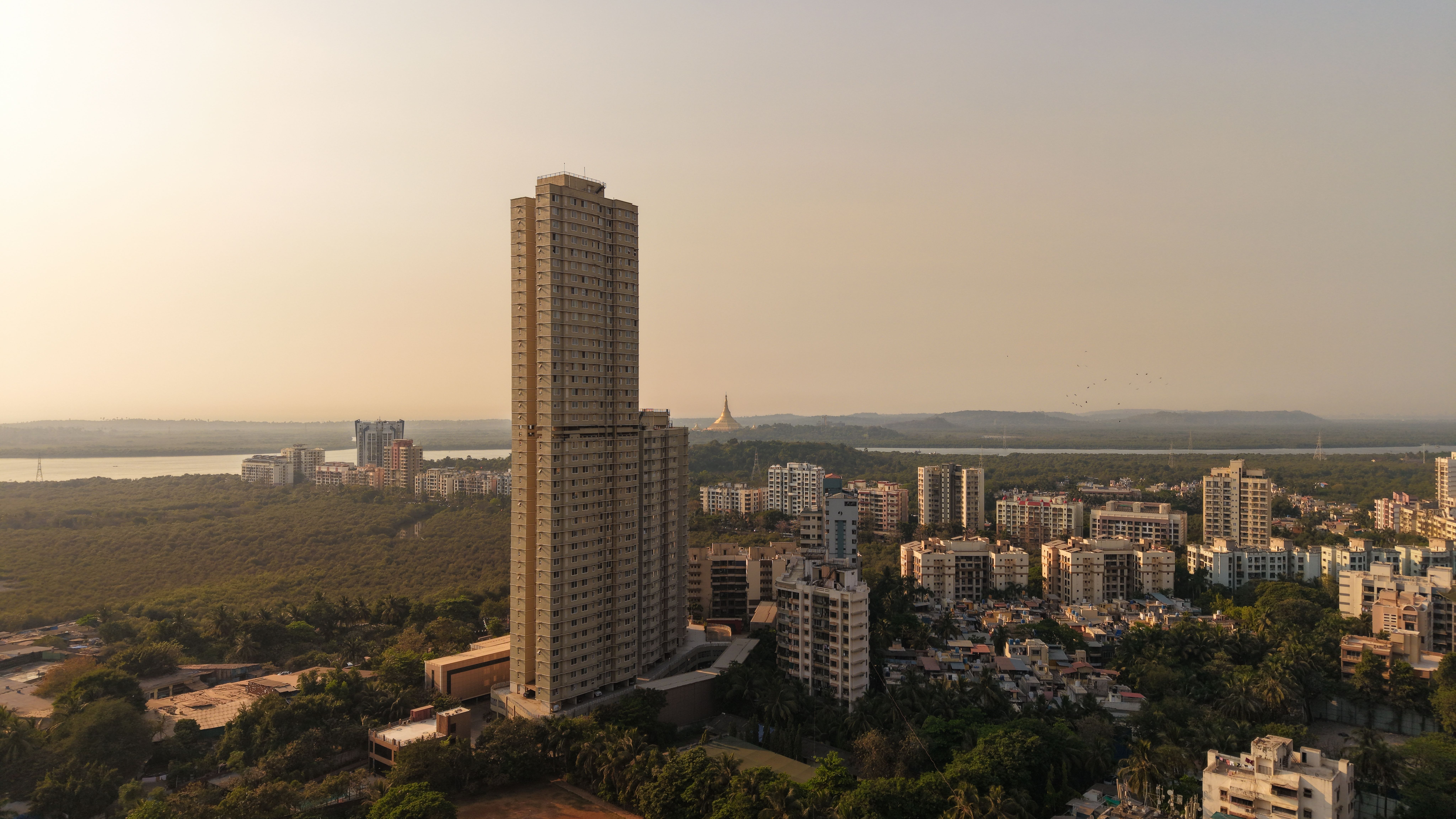 A captivating aerial shot of Mumbai's skyline with tall buildings and lush greenery at sunset.