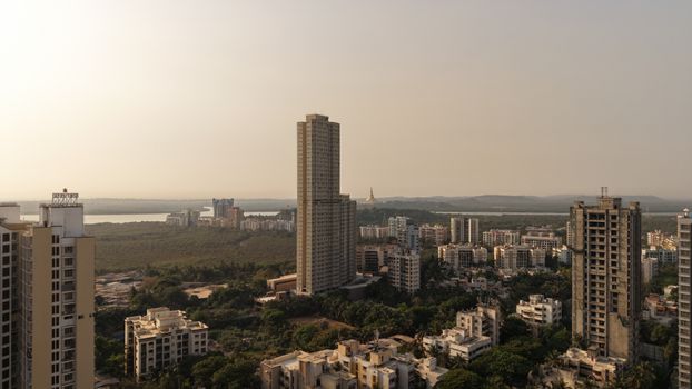 Aerial view of Mumbai skyline with tall buildings and green areas during the day.