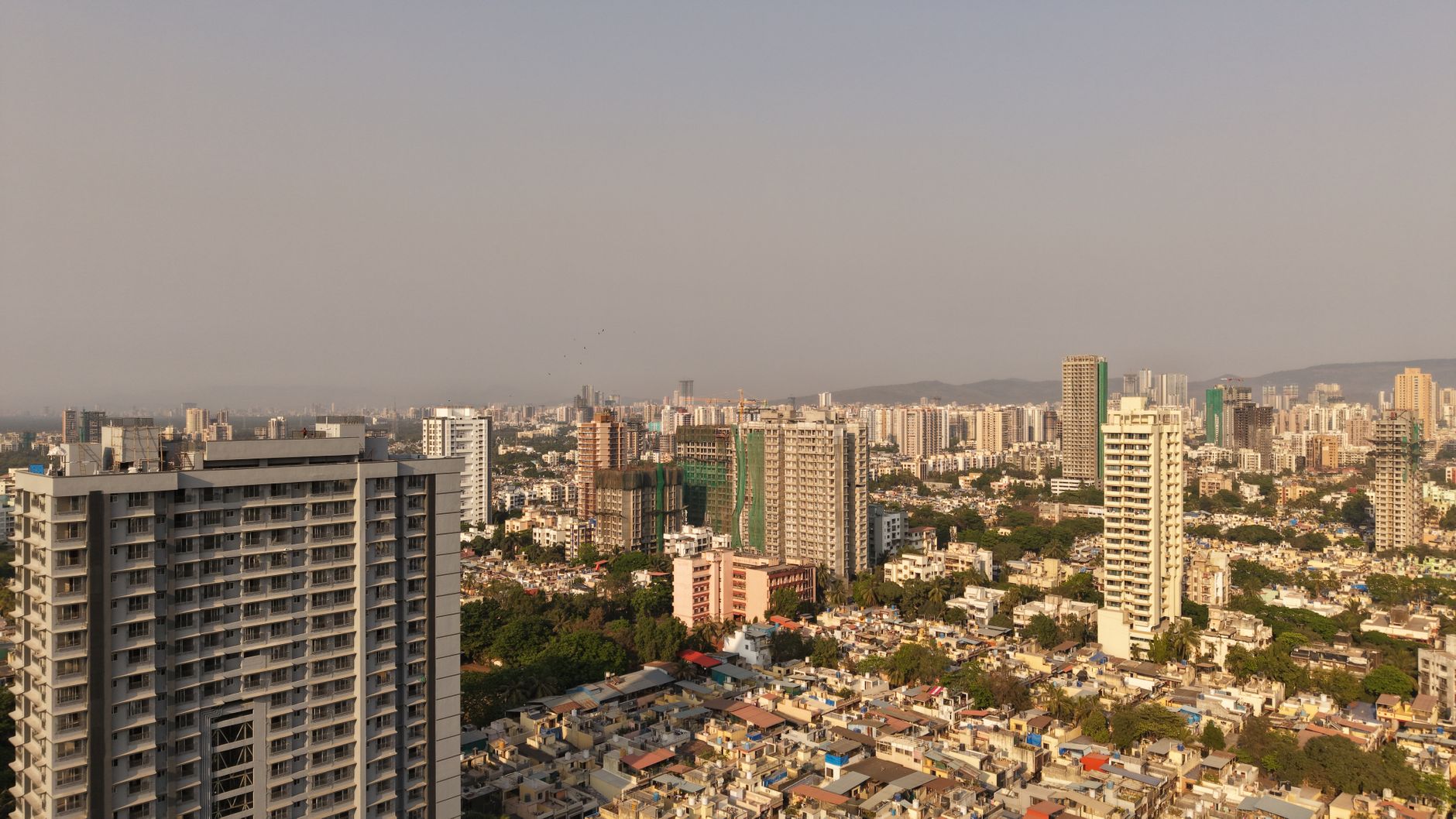 A wide aerial view of the Mumbai skyline showcasing urban architecture and city development during the day.