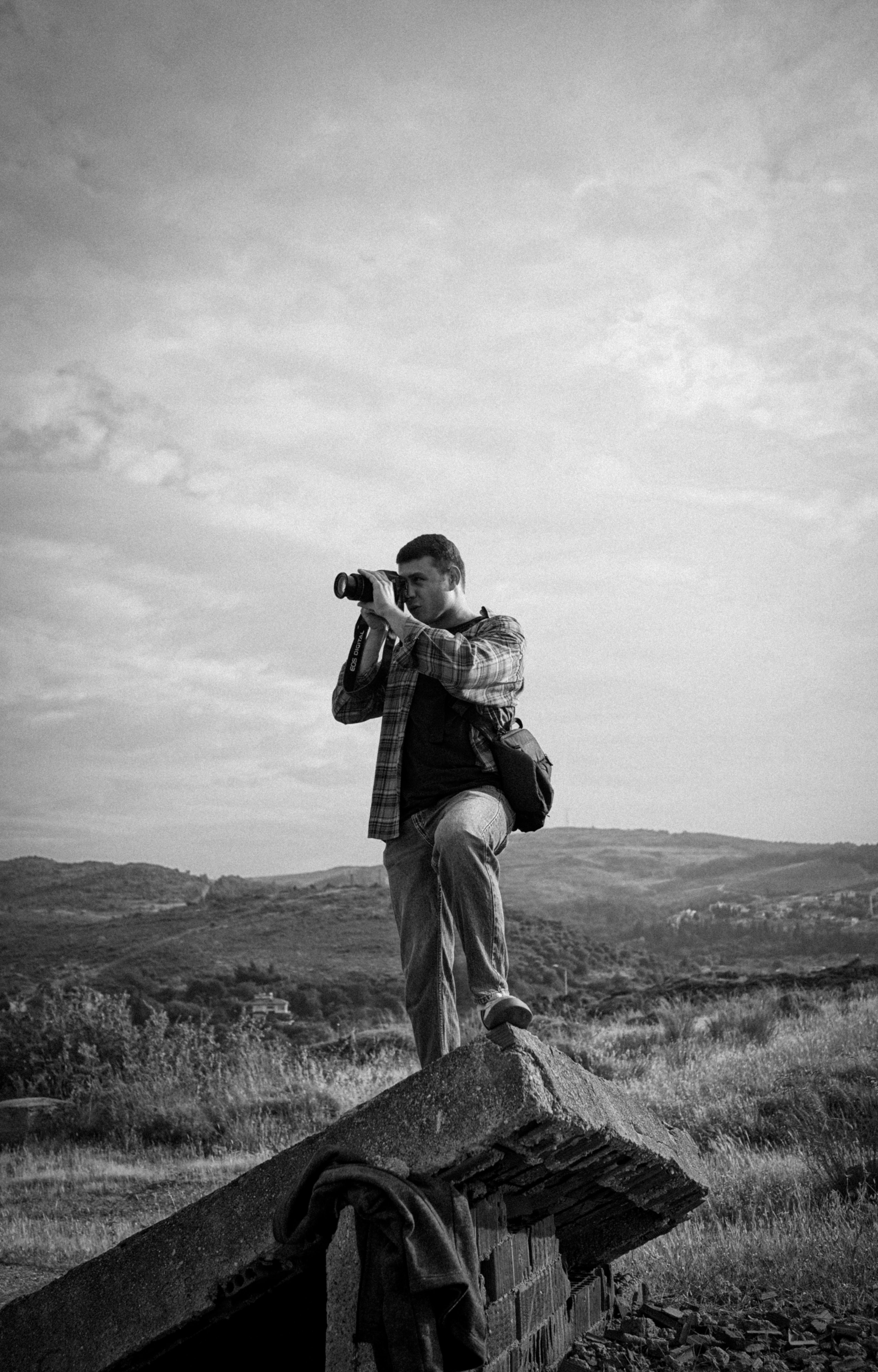 A photographer standing on rocks, taking photos of a scenic landscape.