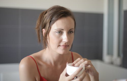Woman in Red Tank Top Holding White Ceramic Mug