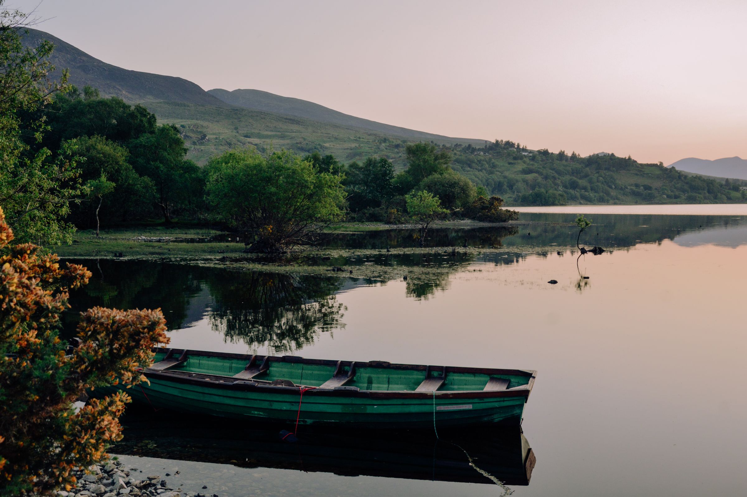 Lakeside view at twilight with a boat and greenery in Ireland