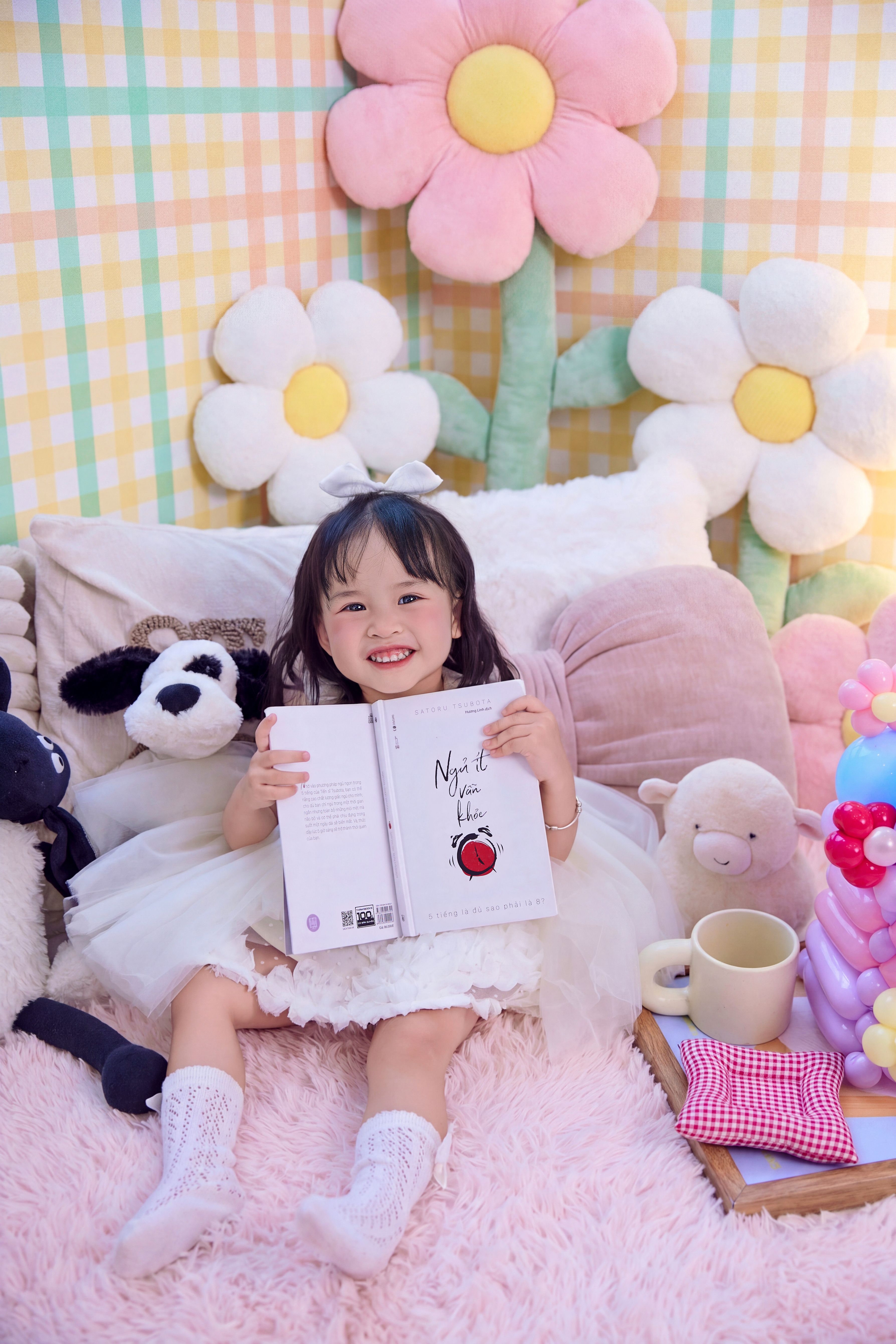 Adorable child enjoying a storybook in a playful and cozy room filled with plush toys.