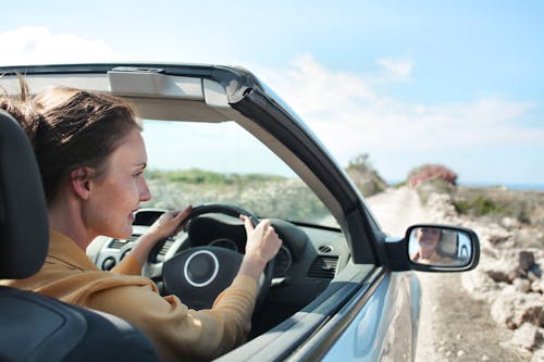 車を運転する茶色のジャケットの女性