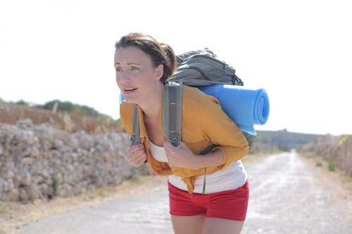 Woman in Brown Long Sleeve Shirt and Red Shorts Carrying Gray Packpack