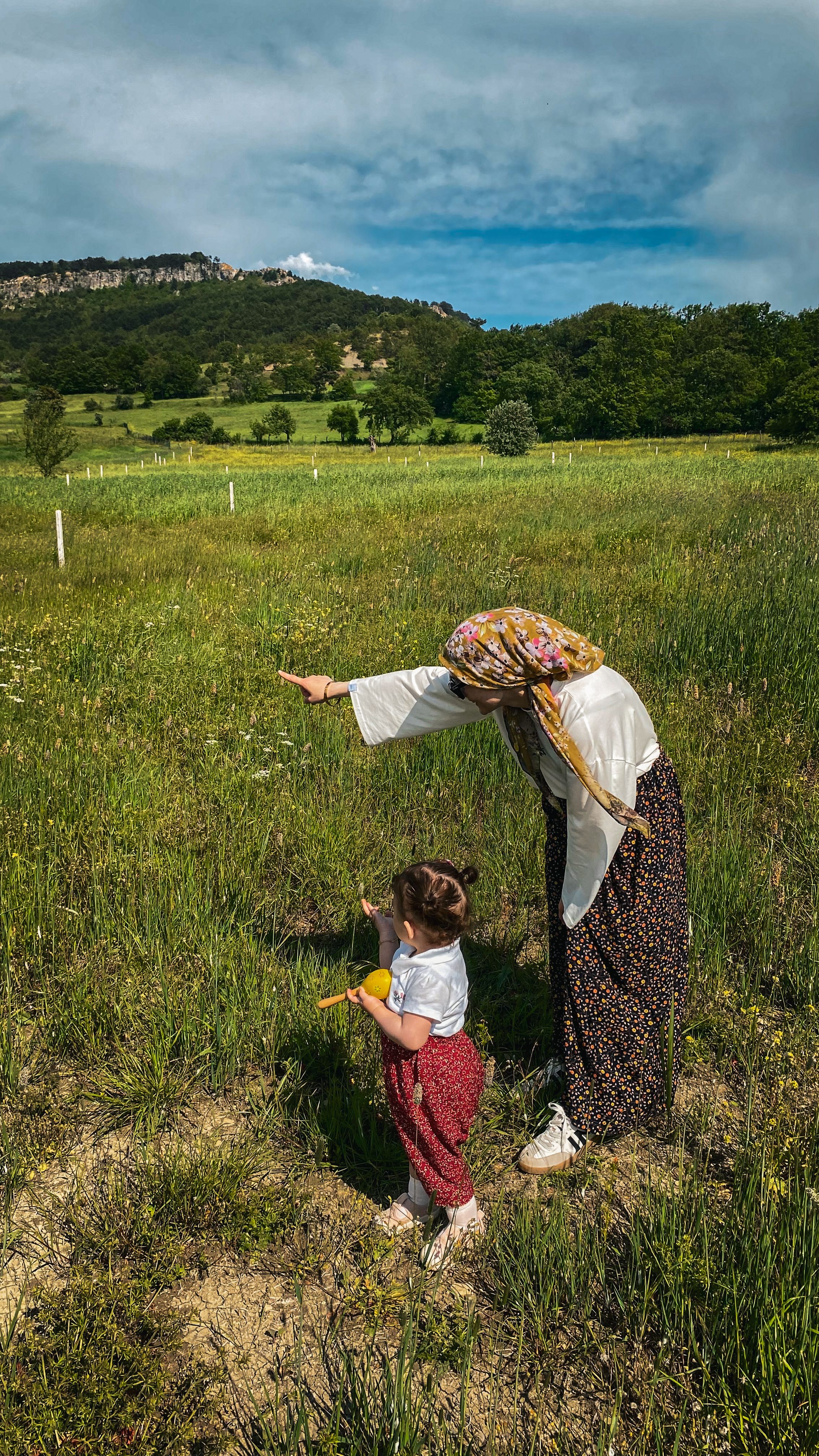A mother and child enjoying a sunny summer day in a scenic countryside meadow.