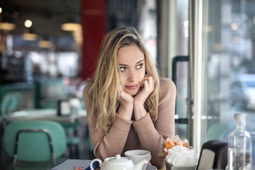 Woman in Brown Long Sleeve Shirt Sitting by the Table