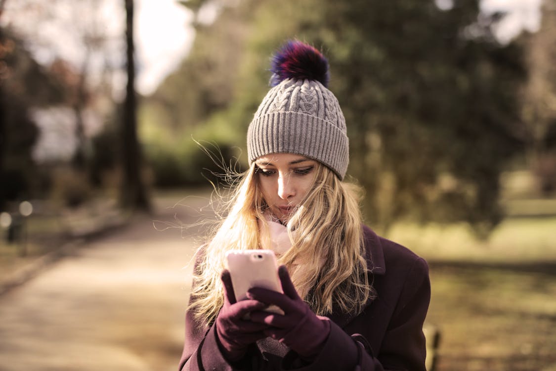Free Женщина в фиолетовом пальто держит белый смартфон Stock Photo