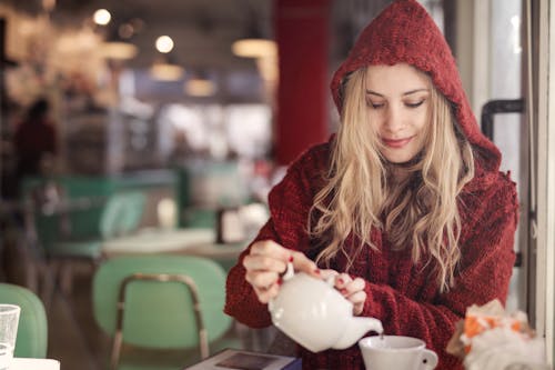 拿著白色陶瓷茶杯的紅色毛衣的女人