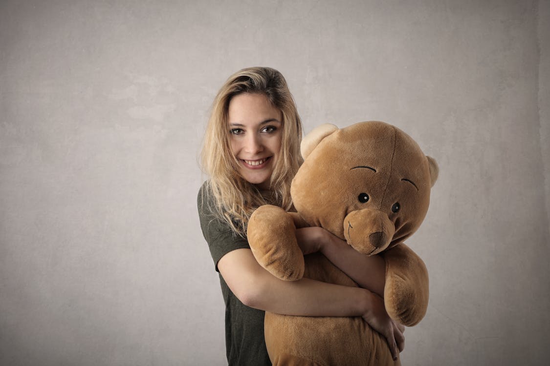 Free Woman in Gray Shirt Hugging Brown Bear Plush Toy Stock Photo