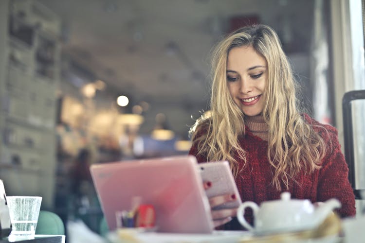 Woman In Red Sweater Holding White Cellphone