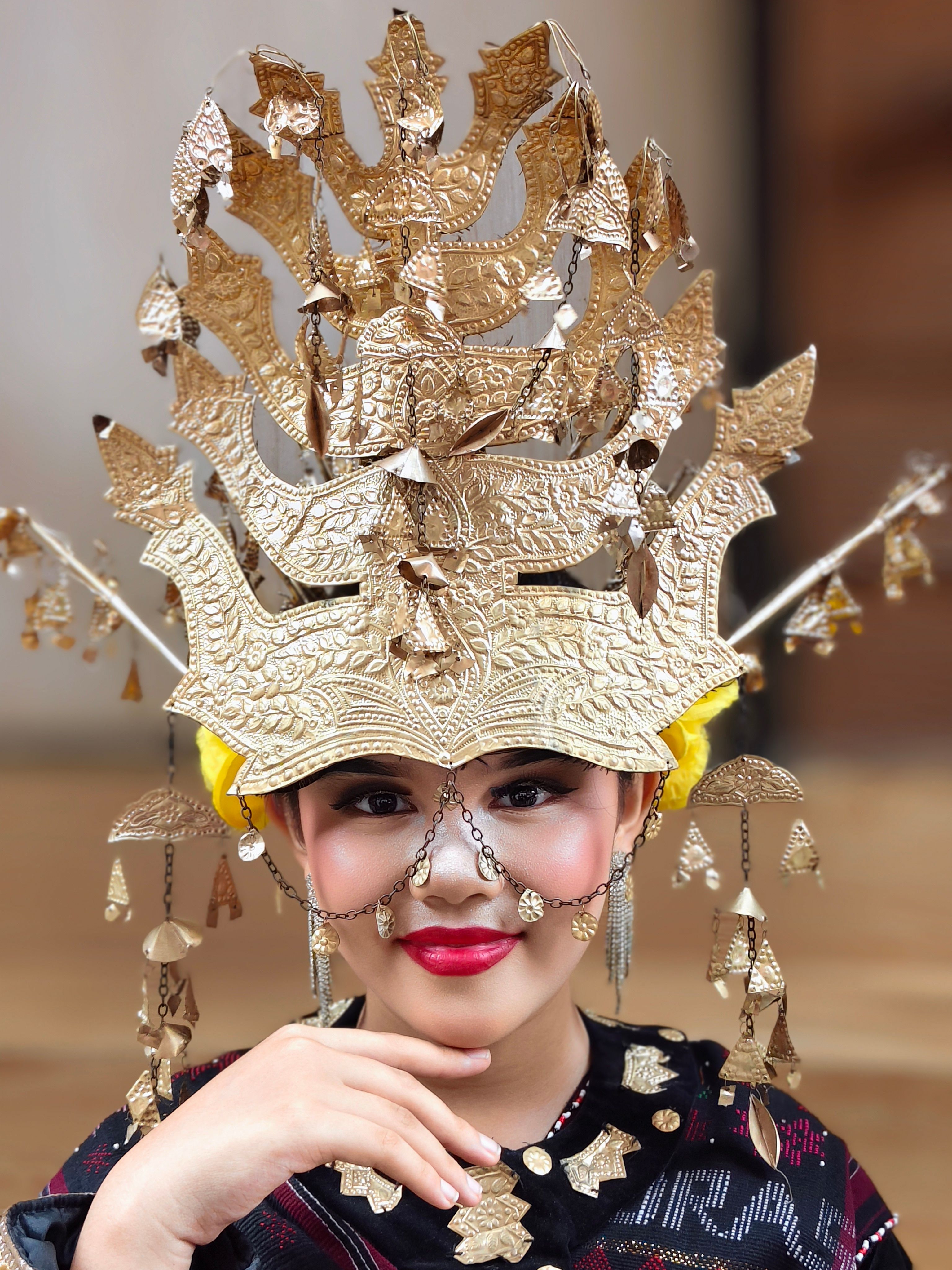 Close-up portrait of a woman wearing a detailed traditional headdress with intricate golden designs.