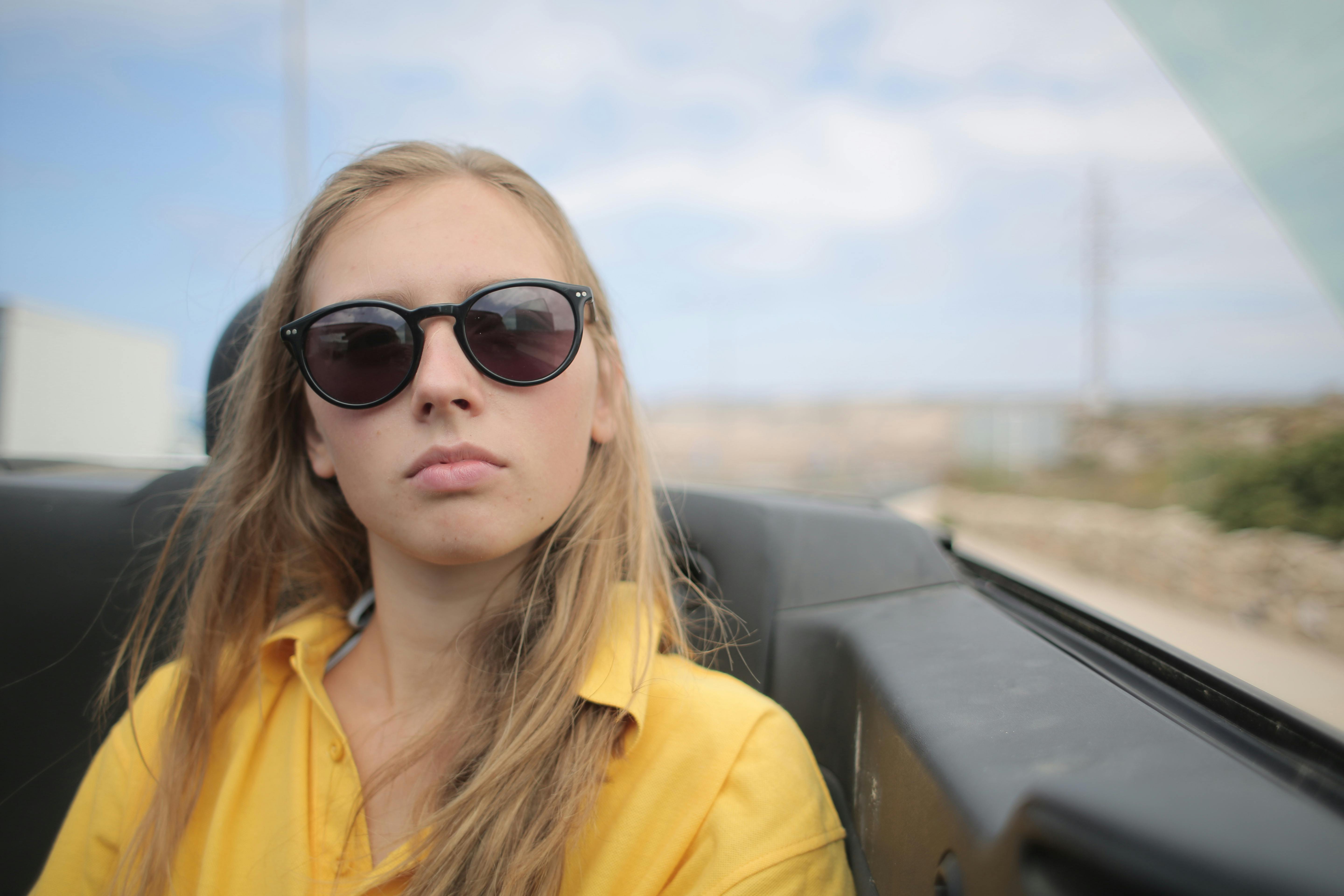 一名年轻女子戴着太阳镜，坐在敞篷车里，享受着悠闲的户外时光
