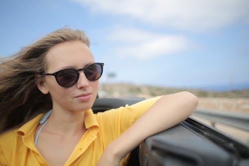 Free Woman in Yellow Polo Shirt Riding a Luxury Car Stock Photo