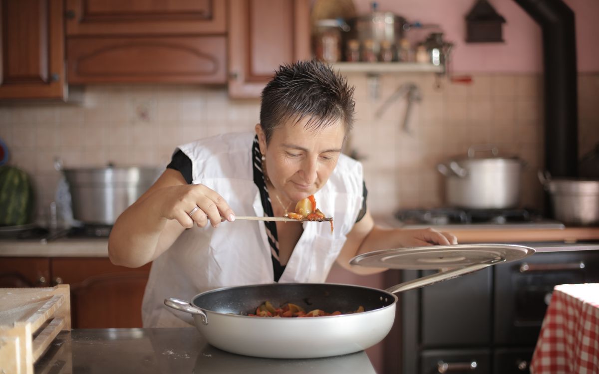 A woman savoring the aroma of a freshly cooked dish in a cozy kitchen setting.