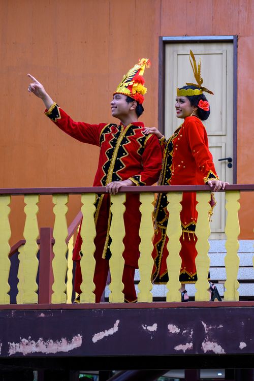 Free Adults in vibrant traditional costumes pose on a balcony, highlighting cultural heritage. Stock Photo