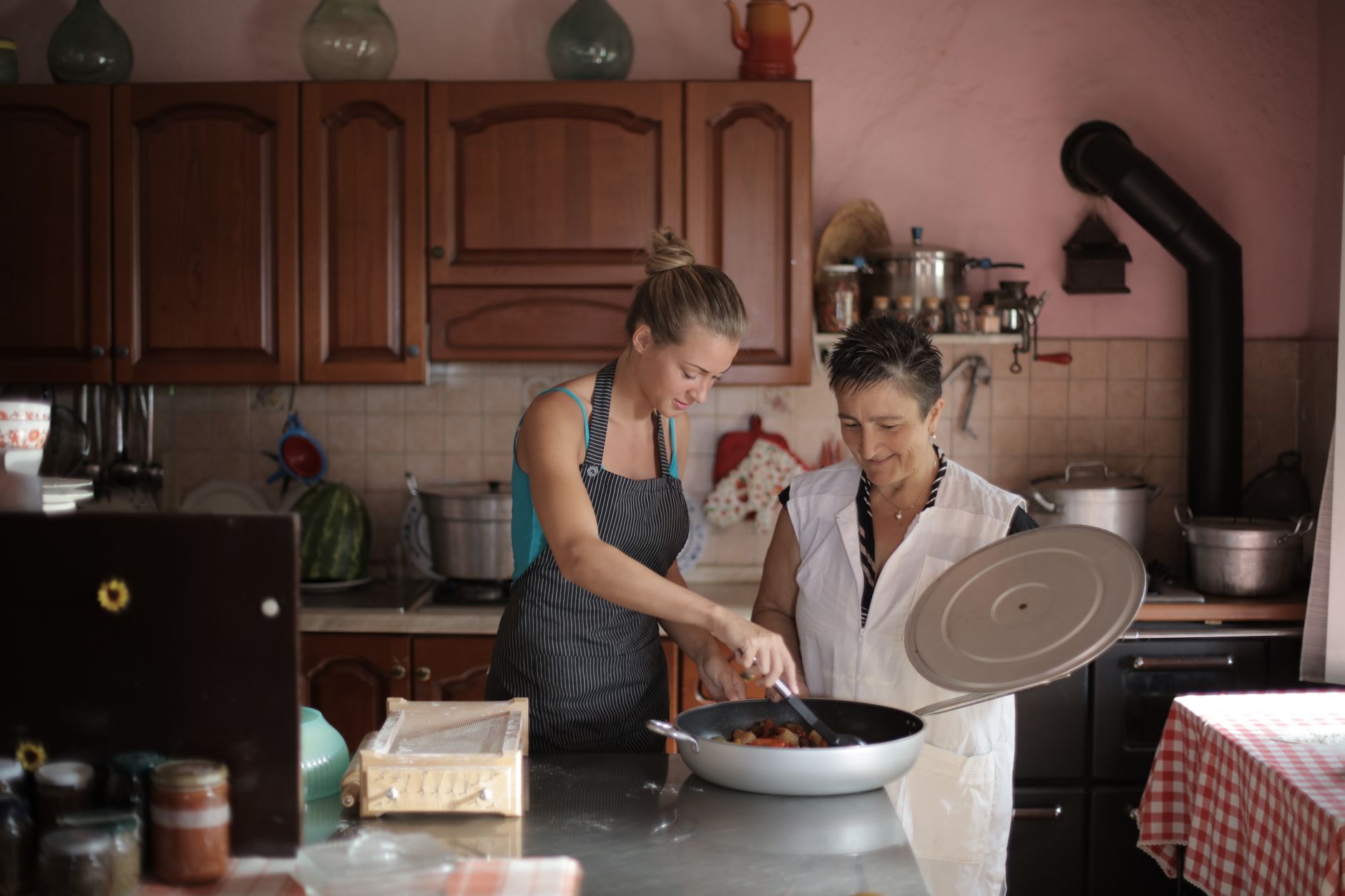 home cook in an apron plating soup at a wooden kitchen counter