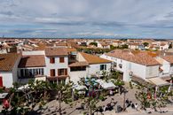 Aerial view of a charming Mediterranean town with a bustling market and tiled rooftops.