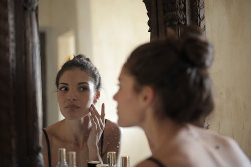 Reflectiefoto Van Vrouw Die Haar Wang Aanraakt