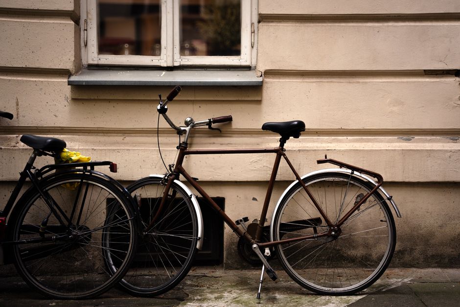 Two vintage bicycles parked against a rustic beige wall, creating a nostalgic urban scene.