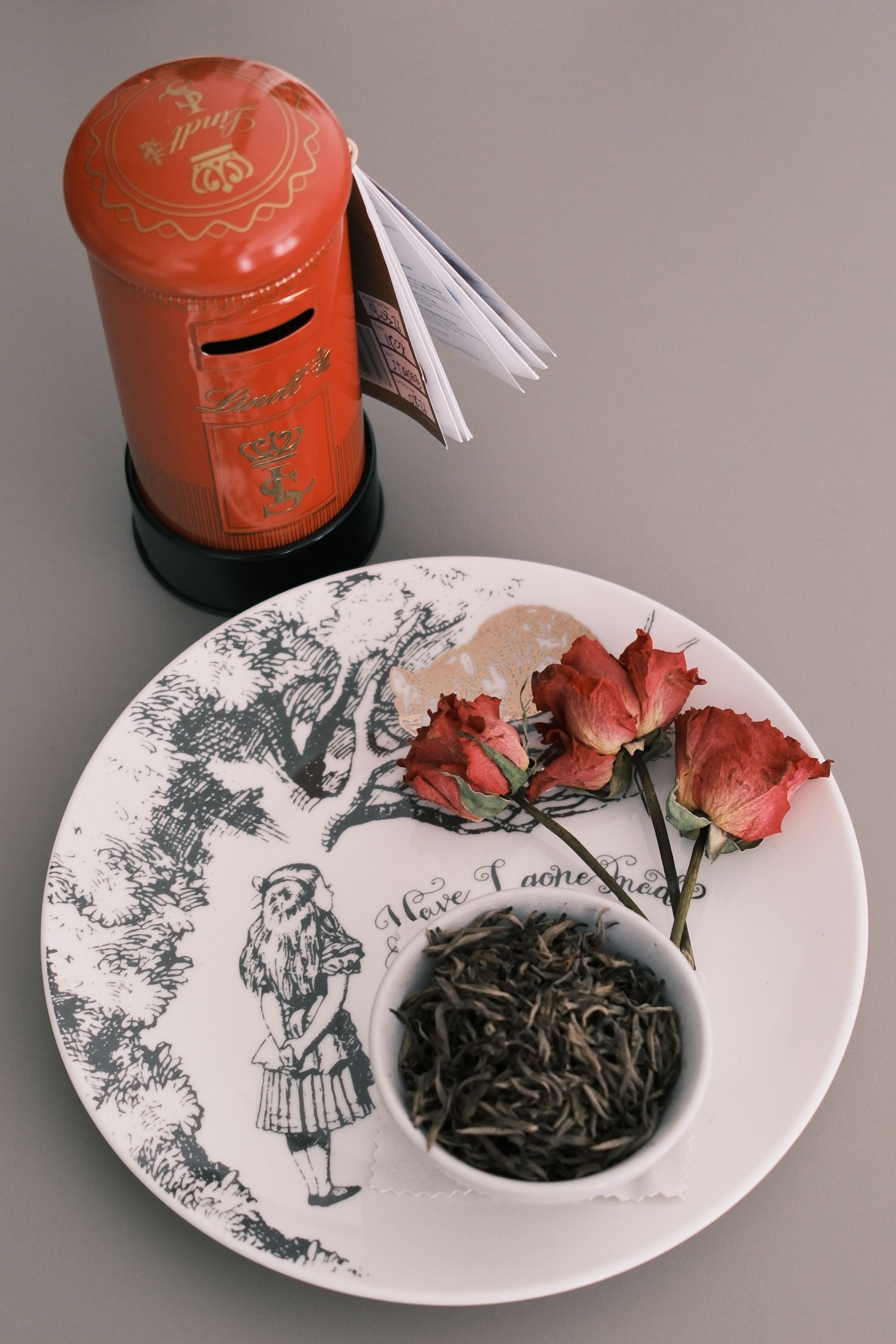 Vintage-style tea set with roses and a red post box on a minimalist background.