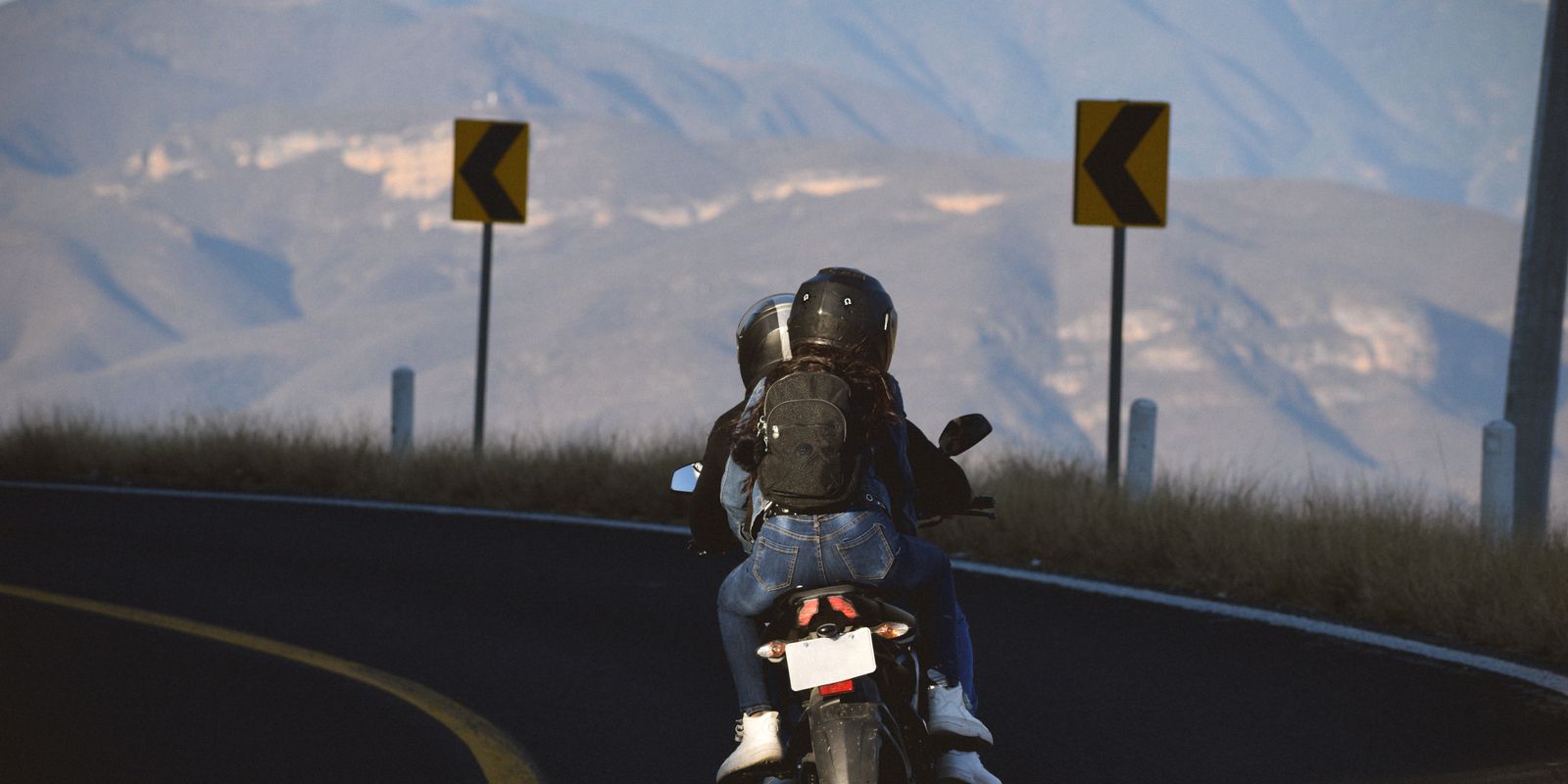 A couple riding a motorcycle on a winding mountain road