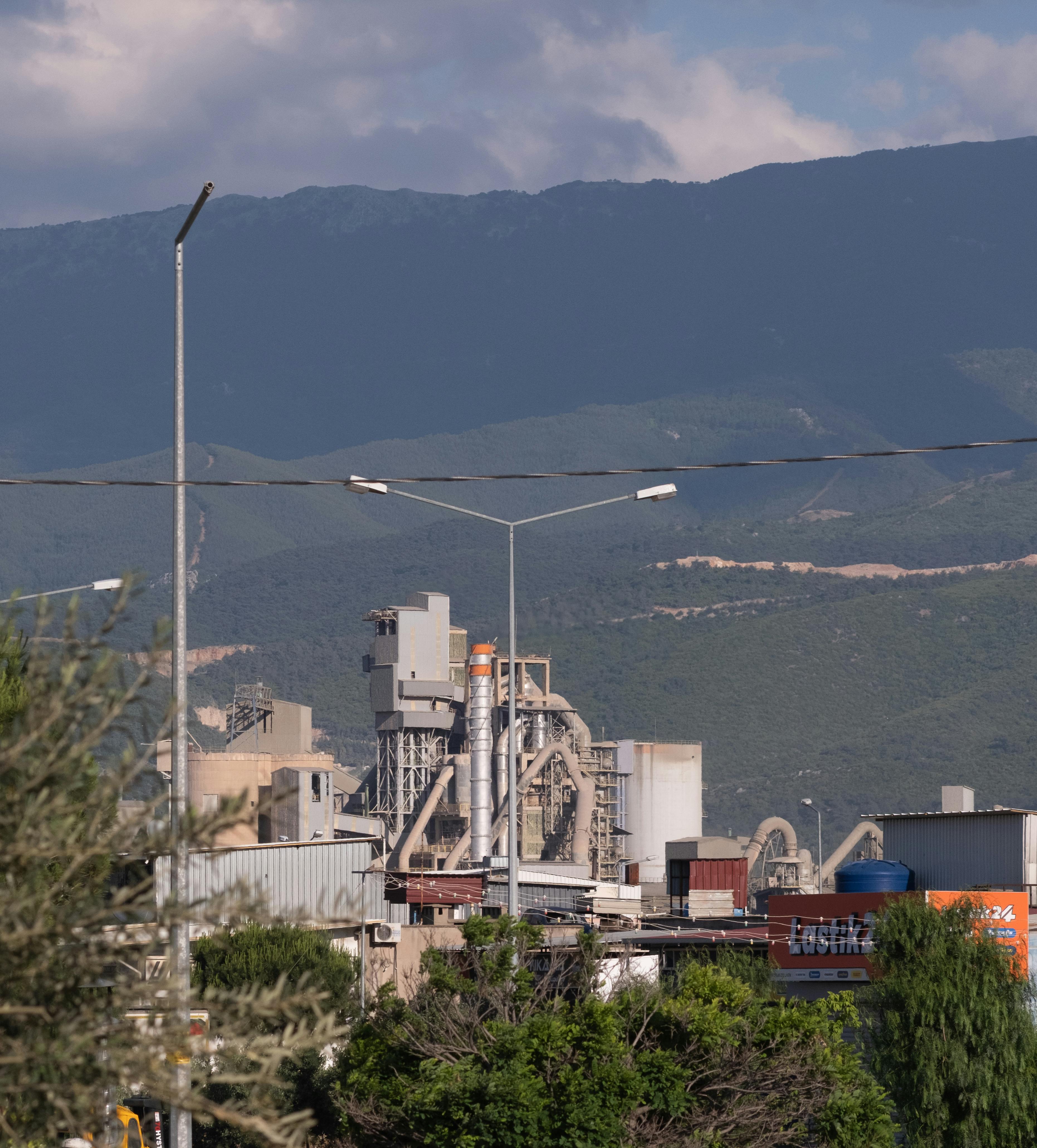 Factory complex with mountain background in Izmir, Türkiye showcasing industrial architecture.