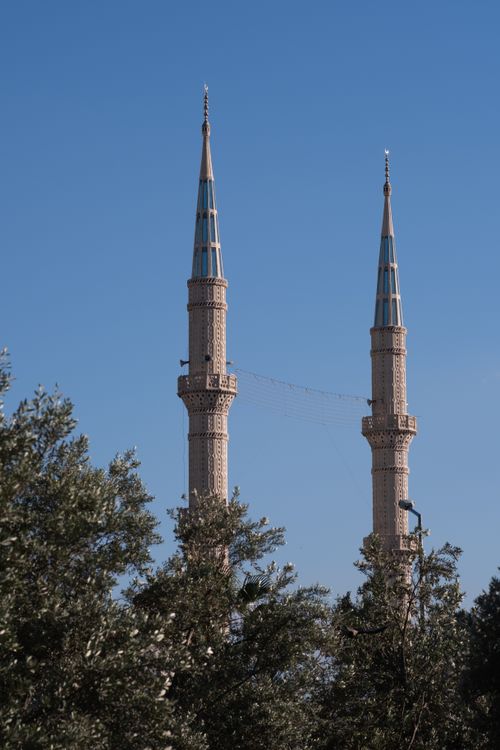 Free Twin minarets rise above greenery on a sunny day in İzmir, Türkiye. Stock Photo