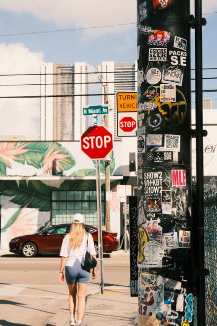 Vibrant street scene featuring stickers, a pedestrian, and Miami Avenue signage, capturing urban lifestyle.