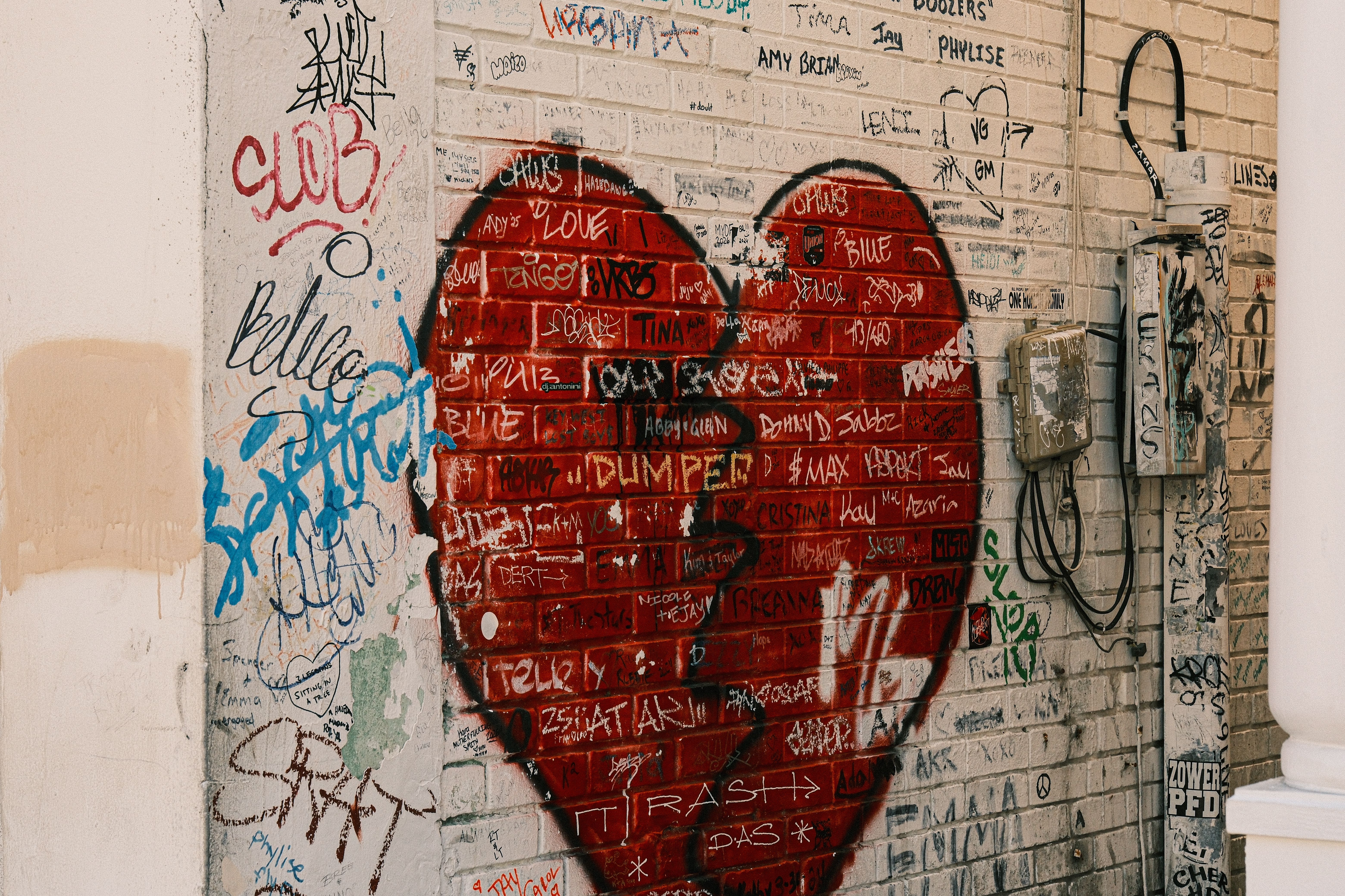 Urban street art featuring a large red heart on a graffiti-covered brick wall.
