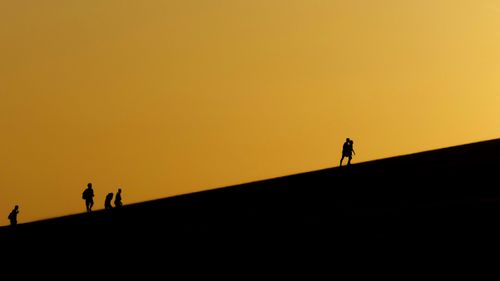 Free Silhouettes of people hiking on sand dunes at sunset in Phan Thiết, Vietnam. Stock Photo