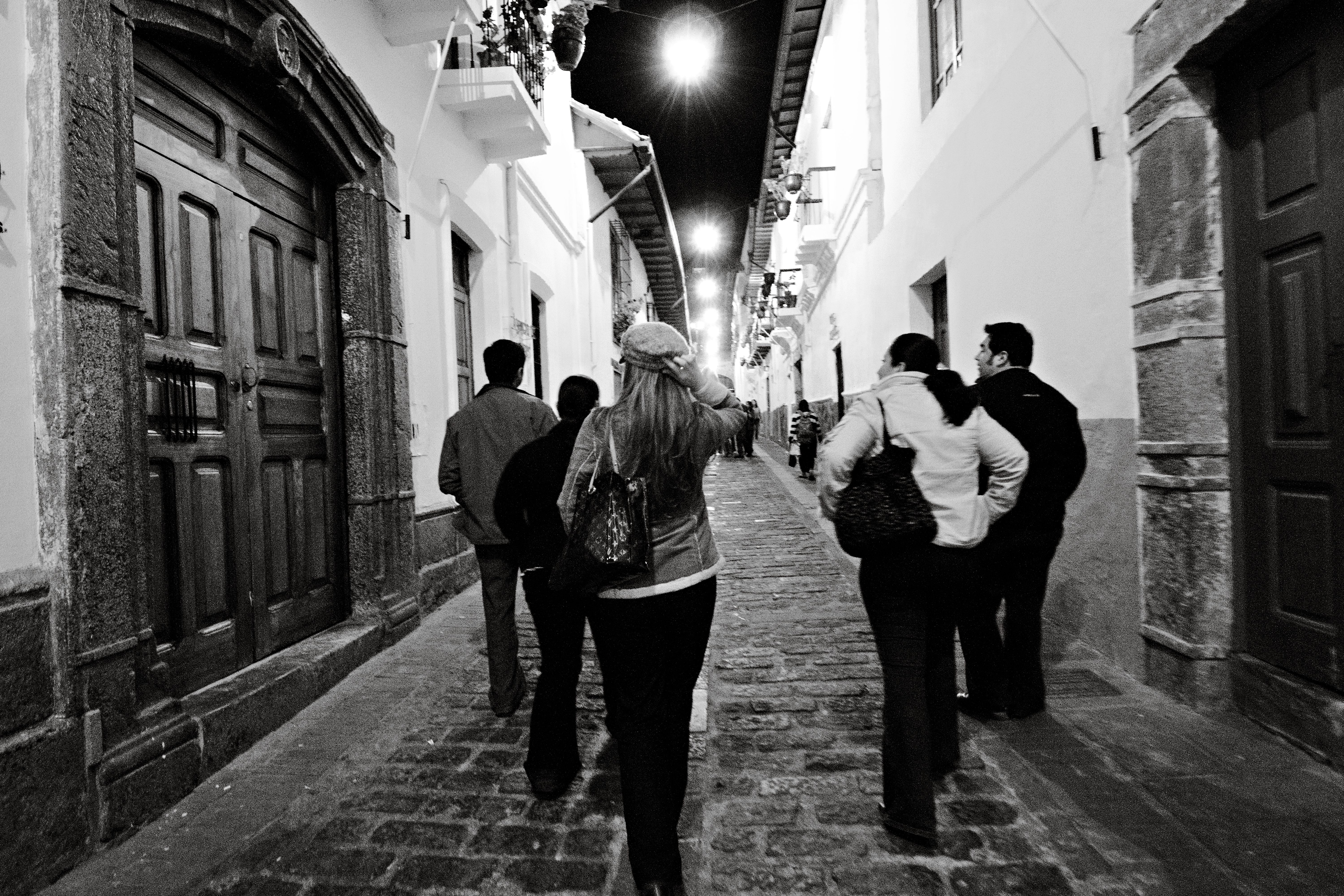 Group of people walking down a charming cobblestone street in Quito at night.
