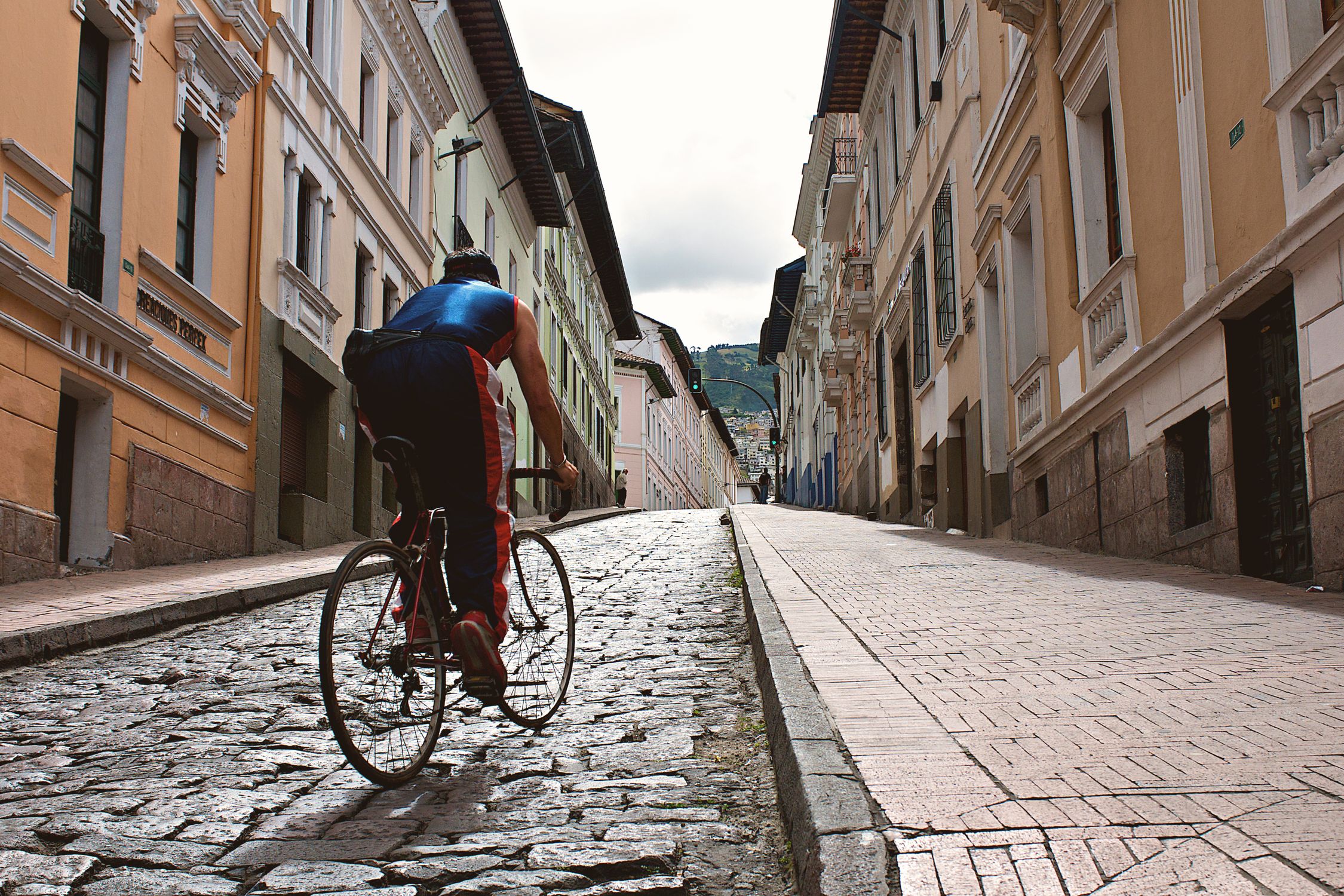 A cyclist rides up a cobblestone street in the historic center of Quito, Ecuador.