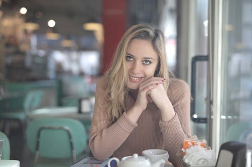 Woman Wearing Sweater While Leaning on Table