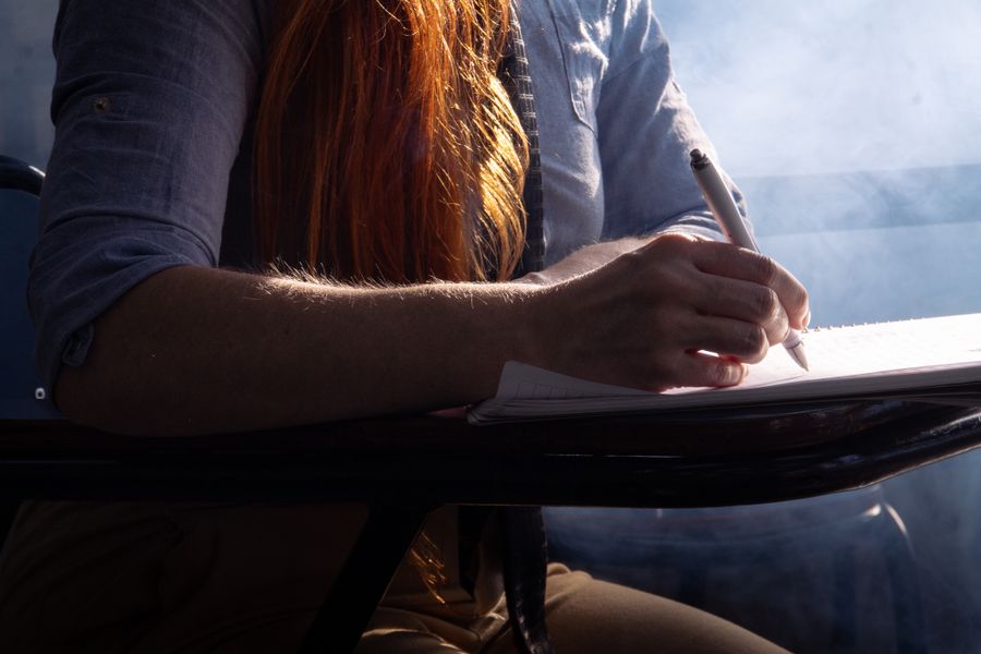 Close-up of a student concentrating on taking notes in a classroom setting with dramatic lighting.