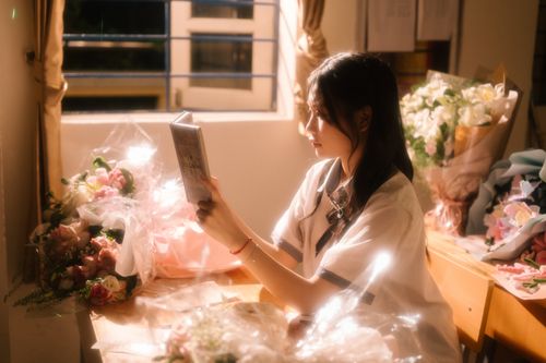 Free Young woman reading by the window surrounded by bouquets of flowers, creating a serene atmosphere. Stock Photo