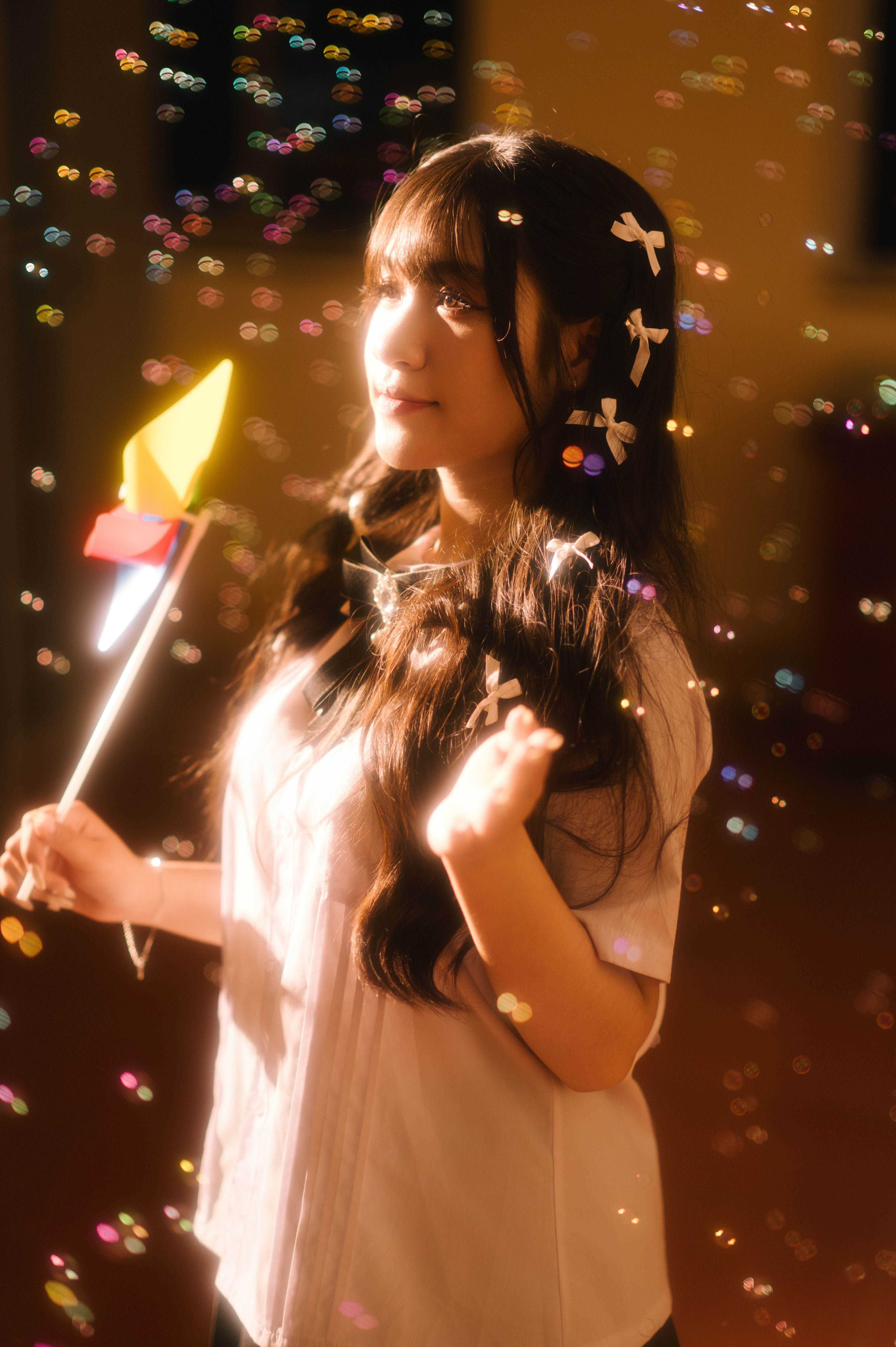 A young woman amidst shimmering lights holding a toy pinwheel in Lạng Sơn, capturing a magical moment.