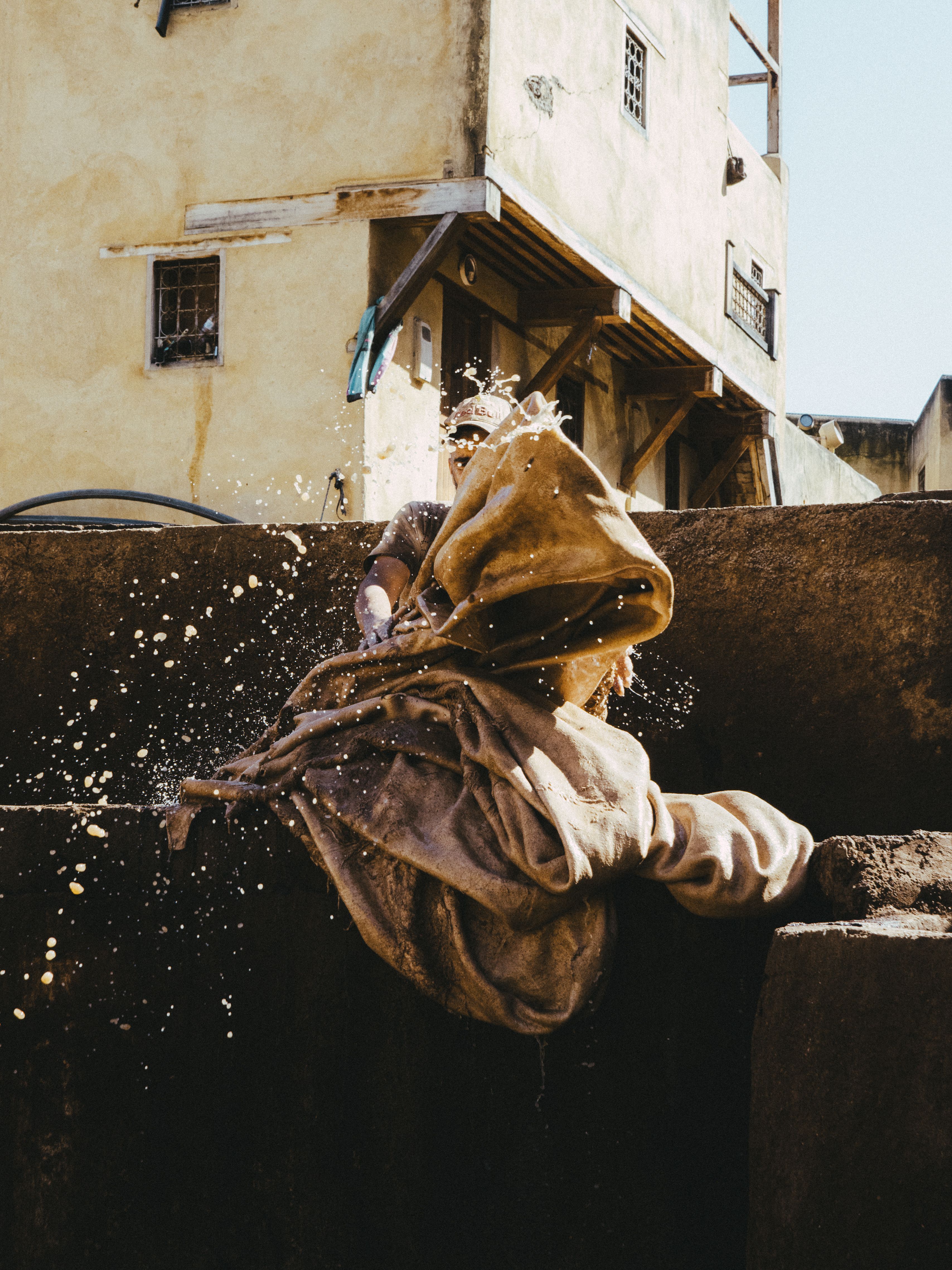 A tanner hard at work in a traditional tannery in Fes, Morocco under the sun.