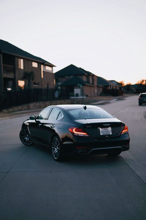 Free A sleek black luxury sedan parked on a quiet residential street during twilight. Stock Photo