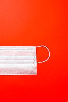 鲜艳红色背景上，外科口罩的特写象征着健康保护