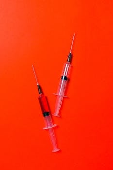 医用注射器的特写镜头被放置在鲜红色表面上，象征着医疗保健