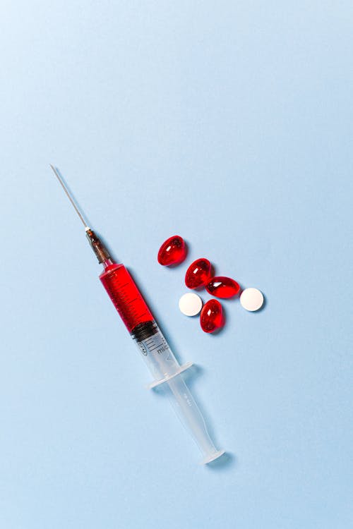 Syringe and Pills on Blue Background